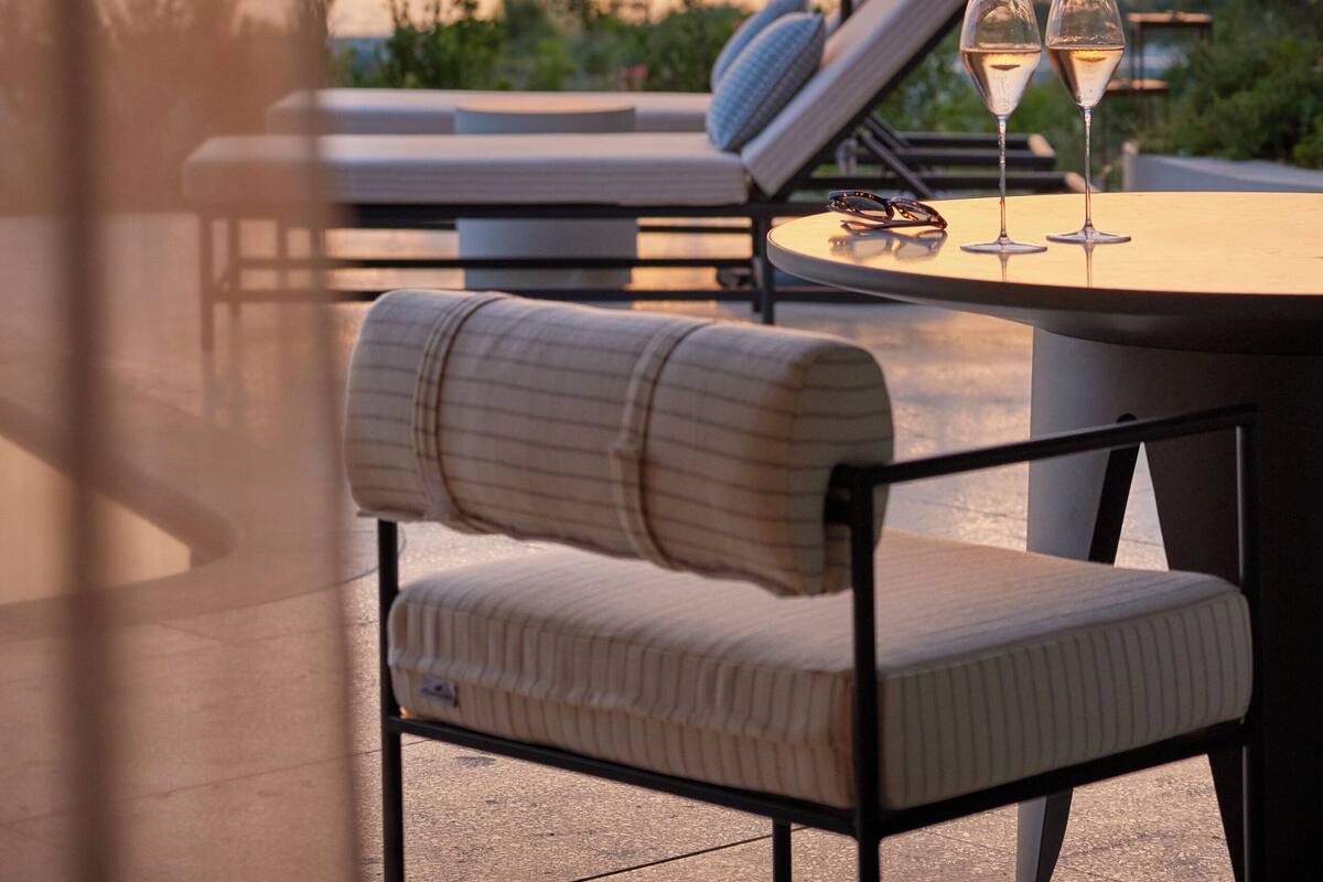 Una terraza con una mesa, dos sillones de descanso, una sombrilla y dos copas de champán.