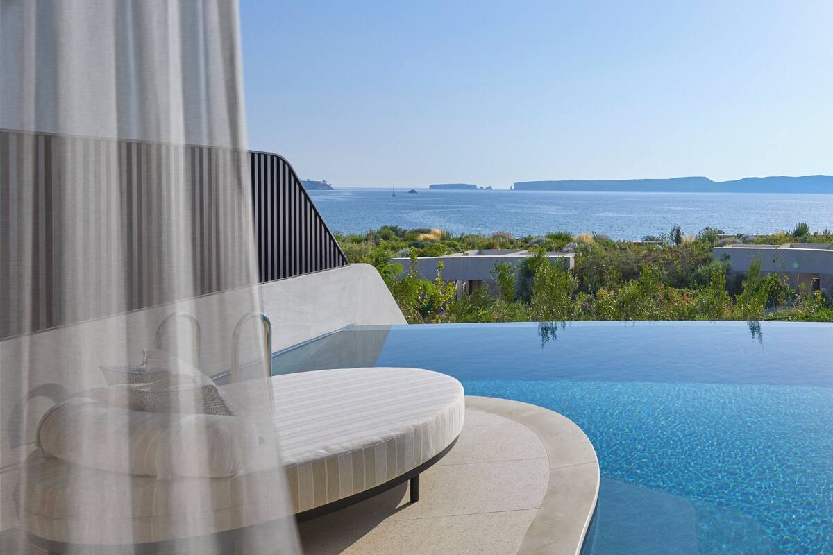 Una piscina infinita moderna con vista despejada al mar y la costa lejana.