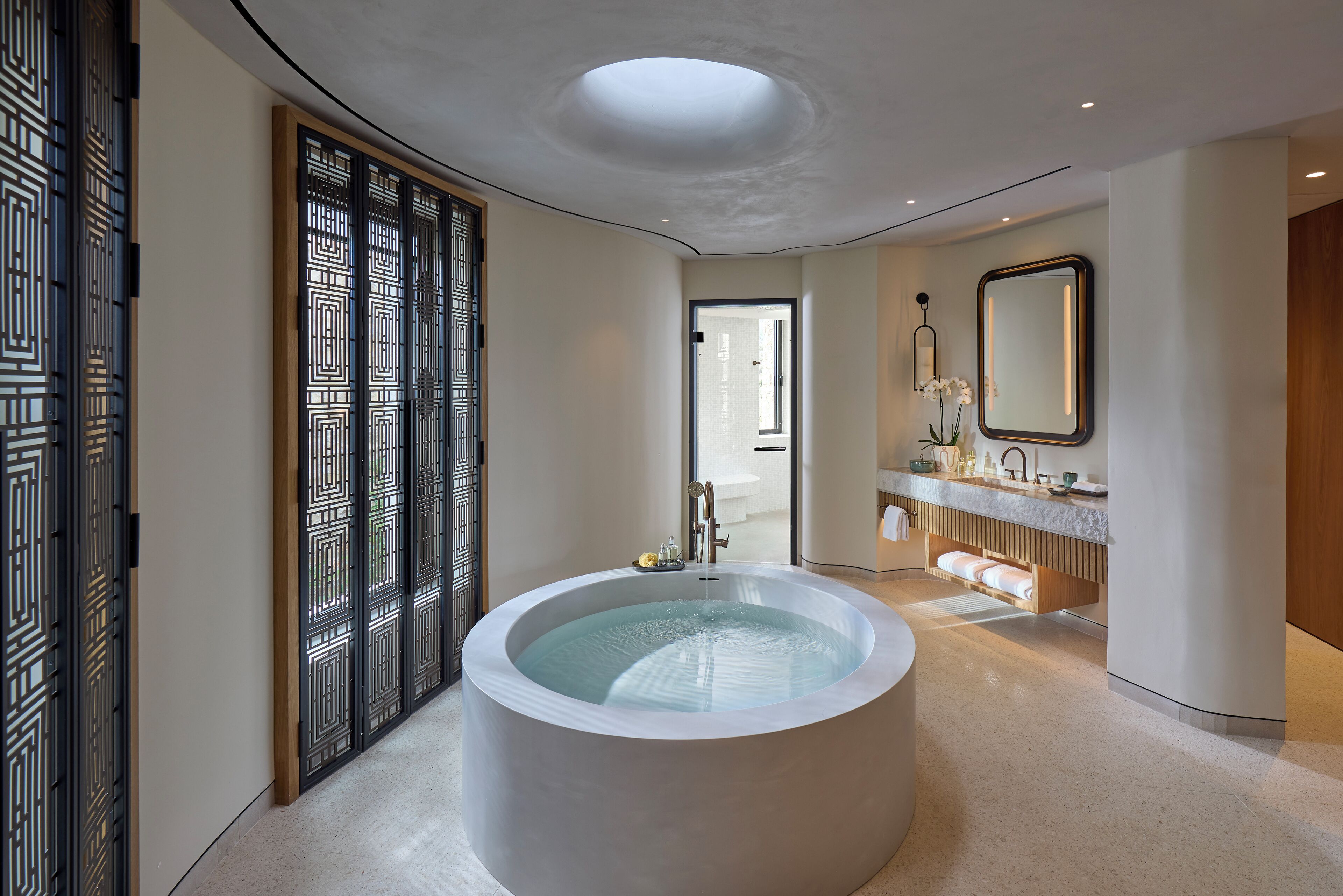A modern bathroom with a large bathtub, a wooden sliding door, and a vanity with a mirror.