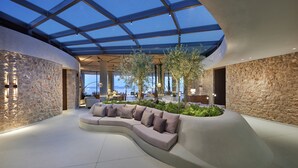 Un interior moderno con una zona de estar curva, paredes de piedra y un techo de cristal.