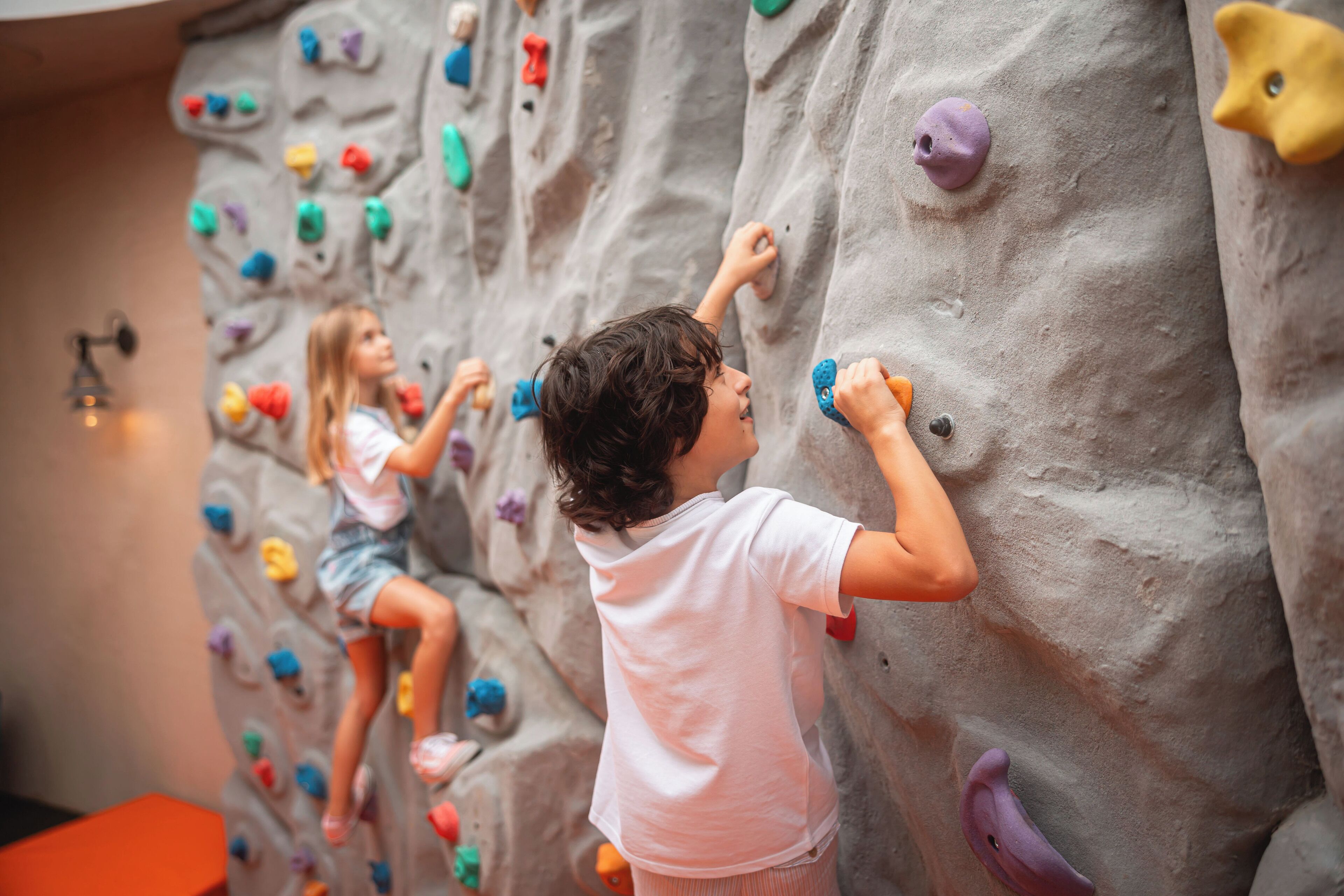 A child climbing a colorful indoor rock wall.