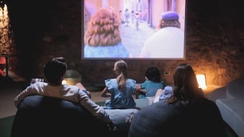A group of people seated in a dimly lit room watching a movie on a large screen.