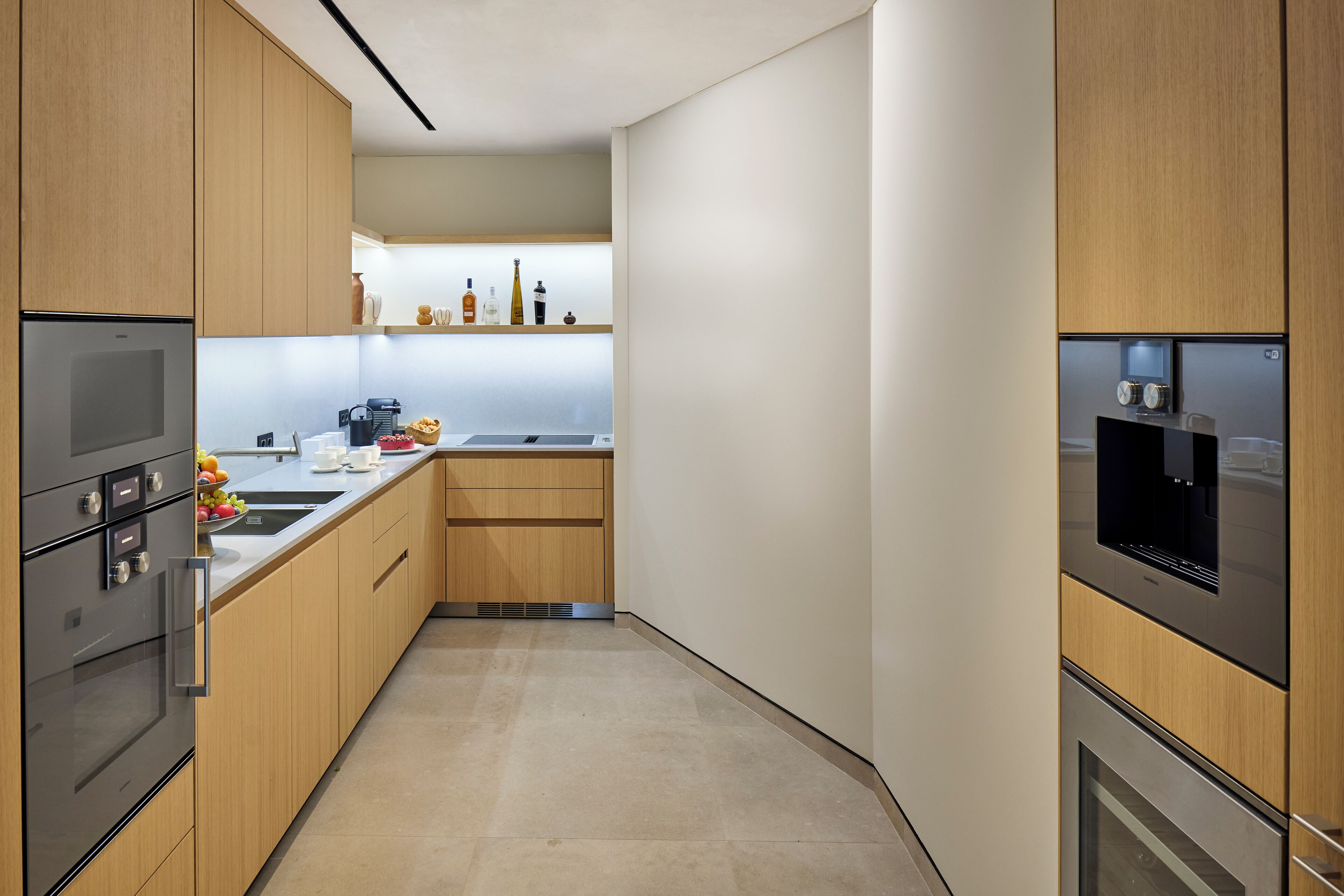 A modern kitchen with wooden cabinets, stainless steel appliances, and a white countertop.