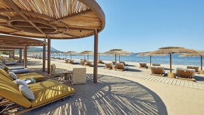 Un resort frente al mar con tumbonas, sombrillas y vistas despejadas al océano.