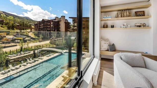 A modern hotel room with a large window overlooking a pool and a mountainous landscape. - Electric Pass Lodge 303 (Snowmass Village)