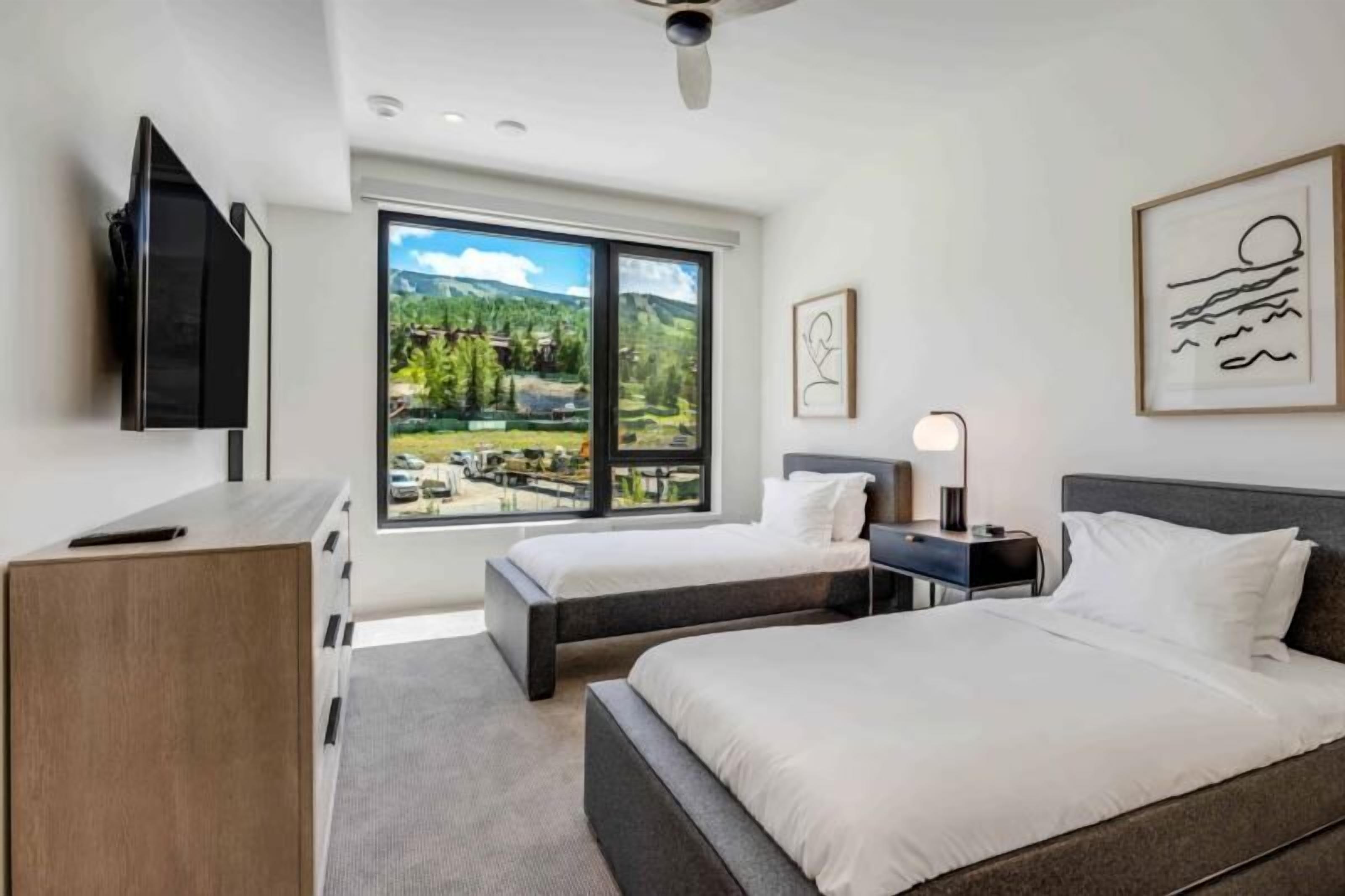 Een moderne hotelkamer met twee bedden, een flatscreen-tv, een bureau en een groot raam met een prachtig uitzicht.