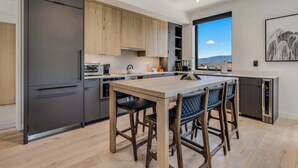 A modern kitchen with a central island, dark cabinetry, and a large window offering a view. - Electric Pass Lodge 508 (Snowmass Village)