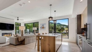 A modern living room with a fireplace, a large TV, and a sofa. - Electric Pass Lodge 509 (Snowmass Village)