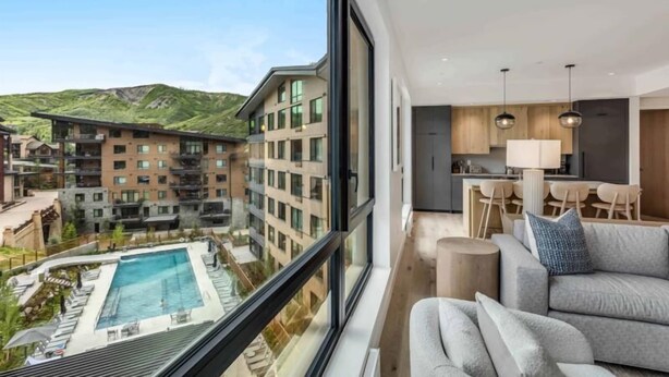 A modern hotel room with a large window overlooking a pool and a mountainous landscape. - Electric Pass Lodge 509 (Snowmass Village)