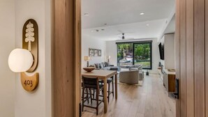 A modern living room with a dining area, large windows, and a view of the outdoors.
