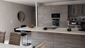 Une cuisine moderne avec des meubles de couleur grise, un îlot central, un four à micro-ondes, un four traditionnel et un évier.