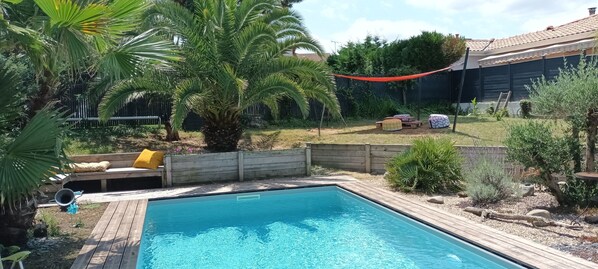 A rectangular swimming pool with a wooden deck, surrounded by a wooden fence and various plants. - Autumn cocoon in Bayonne (Tarnos)