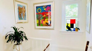 A hallway with two framed artworks, a potted plant, and a window with a bird feeder. - Charming lodging near the beach in De Koog (De Koog)