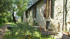 Eine Außenpatio mit Steinmauern, Tischen, Stühlen und Sonnenschirmen.