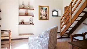 Ein Wohnzimmer mit einem gemusterten Sofa, Holzböden, einem gerahmten Bild und einer Treppe.