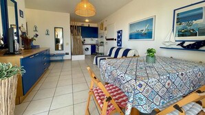 A modern, well-lit room with a dining area, a kitchen, and a bathroom. - Beachside Apartment for 4 in Caorle (Porto Santa Margherita (VE))