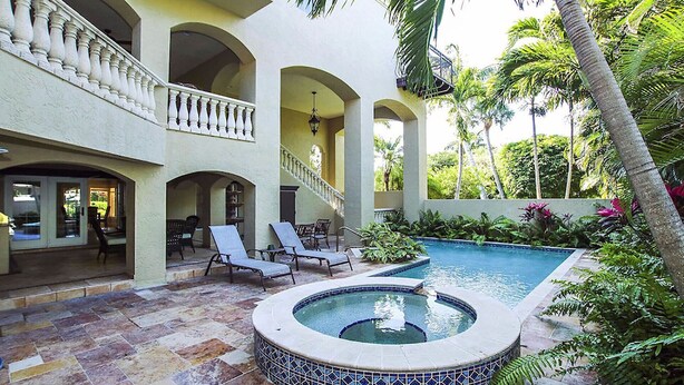 A pool area with a hot tub, lounge chairs, and a staircase leading to an upper level. - Sandcastle Captiva luxurious, 2 minutes from beach, private pool, bay views (Captiva)