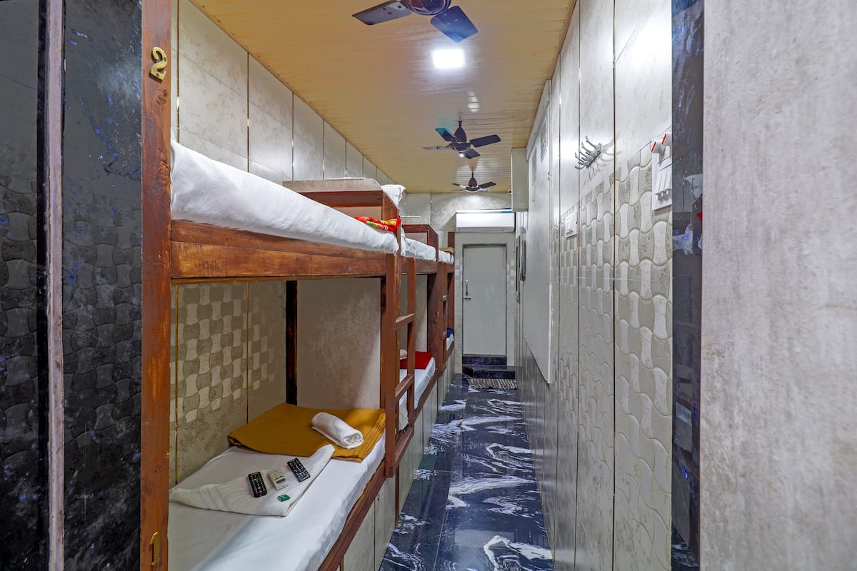 Ein schmaler Flur mit Etagenbetten, einem Deckenventilator und einem gemusterten Boden.