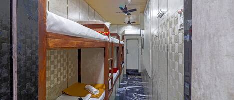 A narrow hallway with bunk beds, a ceiling fan, and a patterned floor.