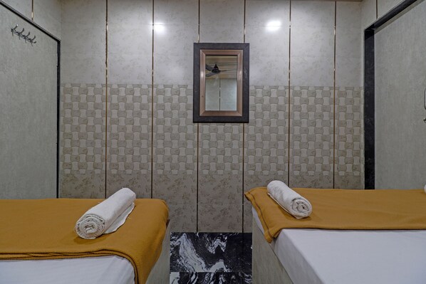 A hotel room with two beds, a mirror, and a patterned wall. - Capital Guest House (Mumbai)