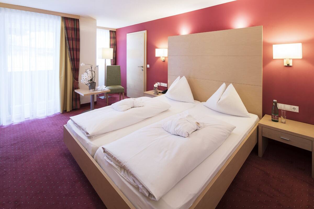Une chambre d’hôtel avec deux lits, un bureau, une chaise, une lampe et une table de chevet.