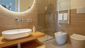 A modern bathroom with a large oval sink, a bidet, a glass-enclosed shower, and a mirror with a wooden frame. - NEW, REFINED, ELEGANT AND EXCLUSIVE APARTMENT LOCATED IN THE CENTER OF THE CITY. (Agrigento)
