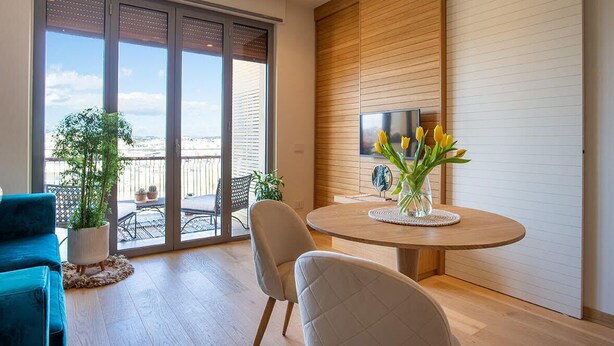 A modern living room with a round table, two chairs, a potted plant, and a view through large sliding doors to an outdoor balcony. - NEW, REFINED, ELEGANT AND EXCLUSIVE APARTMENT LOCATED IN THE CENTER OF THE CITY. (Agrigento)