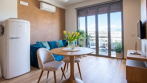 A modern living space with a dining area, a sofa, a table with a vase of flowers, and a large window with a view. - NEW, REFINED, ELEGANT AND EXCLUSIVE APARTMENT LOCATED IN THE CENTER OF THE CITY. (Agrigento)