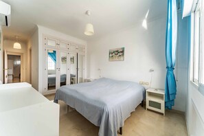 Une chambre à coucher avec un lit, des tables de chevet, une armoire et une fenêtre avec des rideaux.
