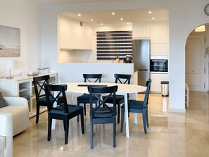 Une cuisine moderne dotée d’un îlot central, de meubles blancs et d’un réfrigérateur en acier inoxydable.