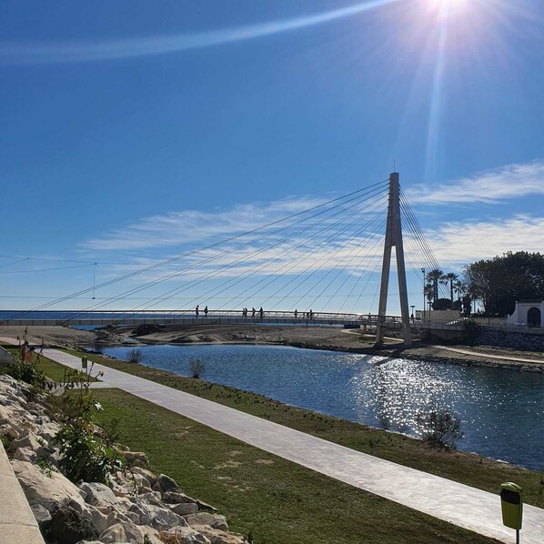 Un pont piétonnier enjambant une étendue d’eau, avec un ciel dégagé.