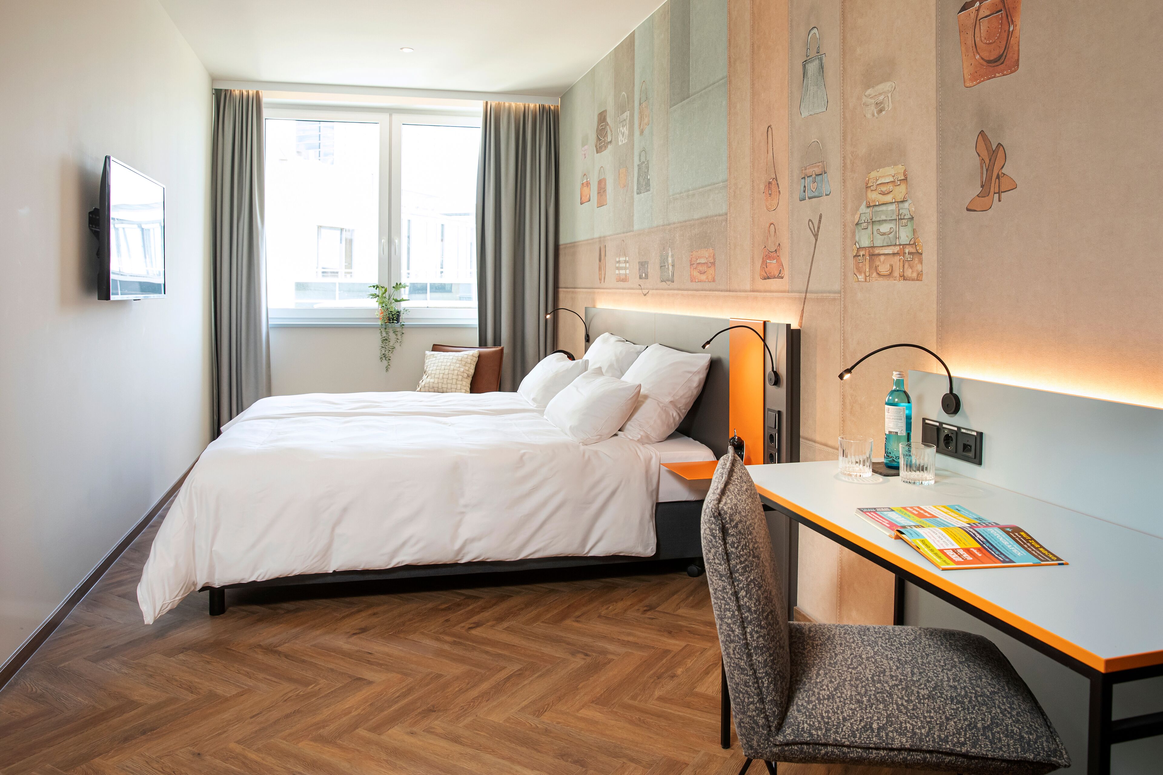 Una habitación de hotel con cama, escritorio, silla, televisor y ventana con cortinas.