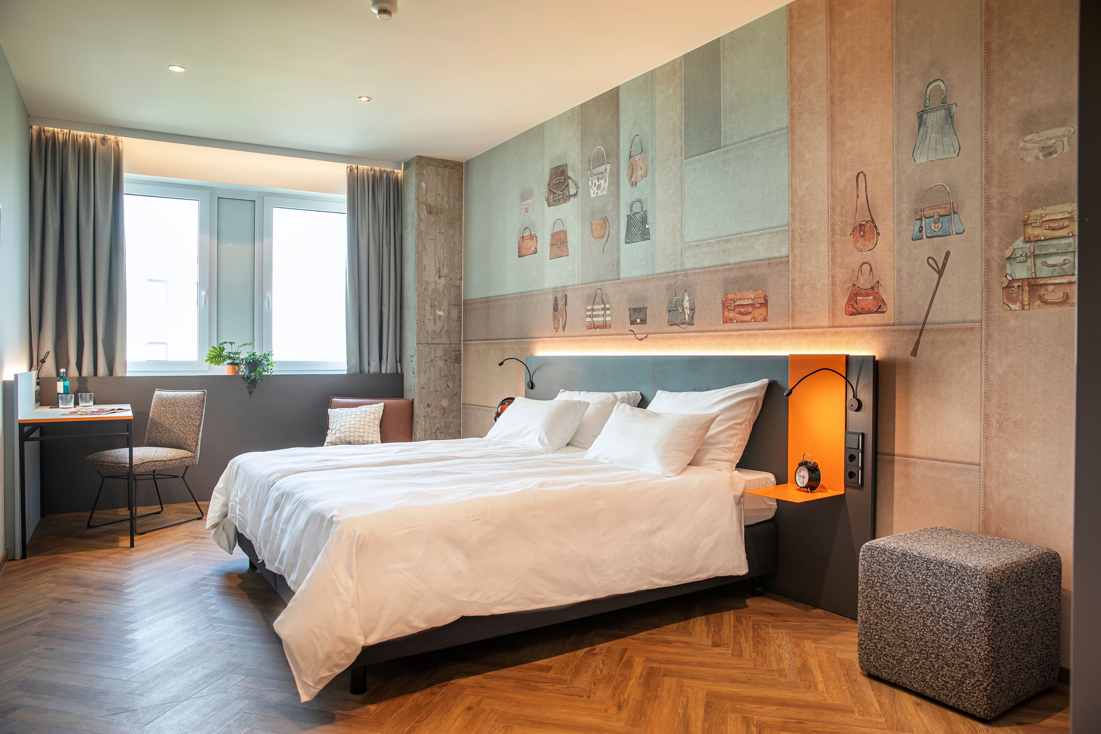Ein Schlafzimmer mit einem großen Bett, einem Schreibtisch und einem Stuhl. An der Wand befinden sich eine Lampe und eine Uhr.