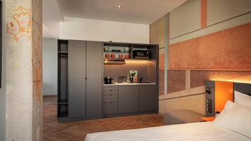 Una habitación de hotel compacta con cama, kitchenette y armario empotrado.