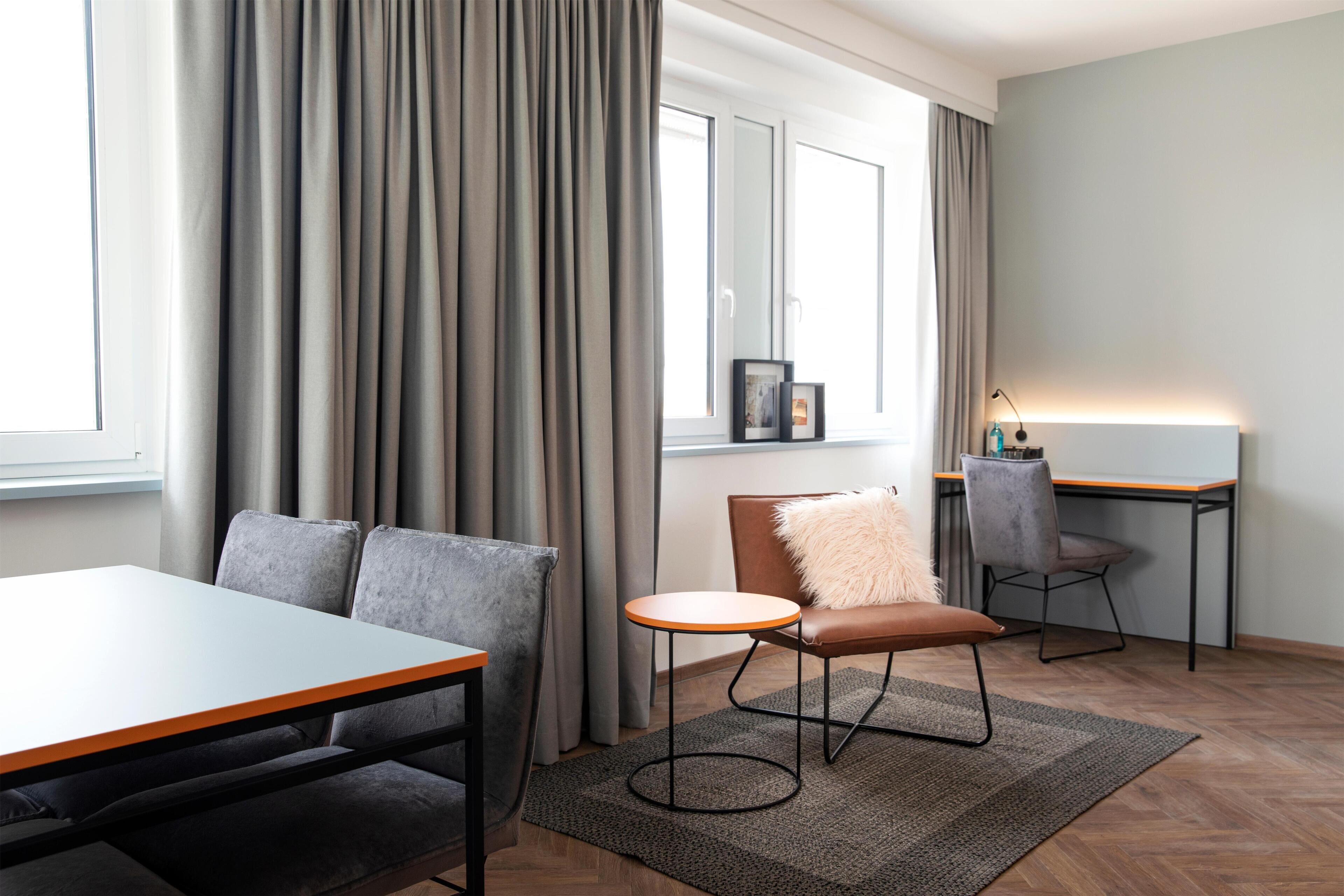 A modern room with a dining table, a sofa, a chair, and a desk.