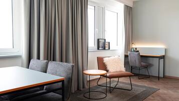 A modern room with a dining table, a sofa, a chair, and a desk.