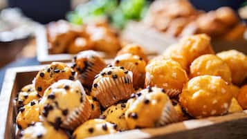 A wooden tray filled with various muffins, some with chocolate chips and others with white toppings.