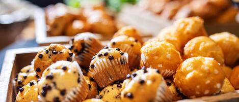 A wooden tray filled with various muffins, some with chocolate chips and others with white toppings.