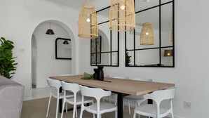 A dining area with a wooden table, white chairs, and two wicker pendant lights. - Alexander Road 7B (Cape Town)