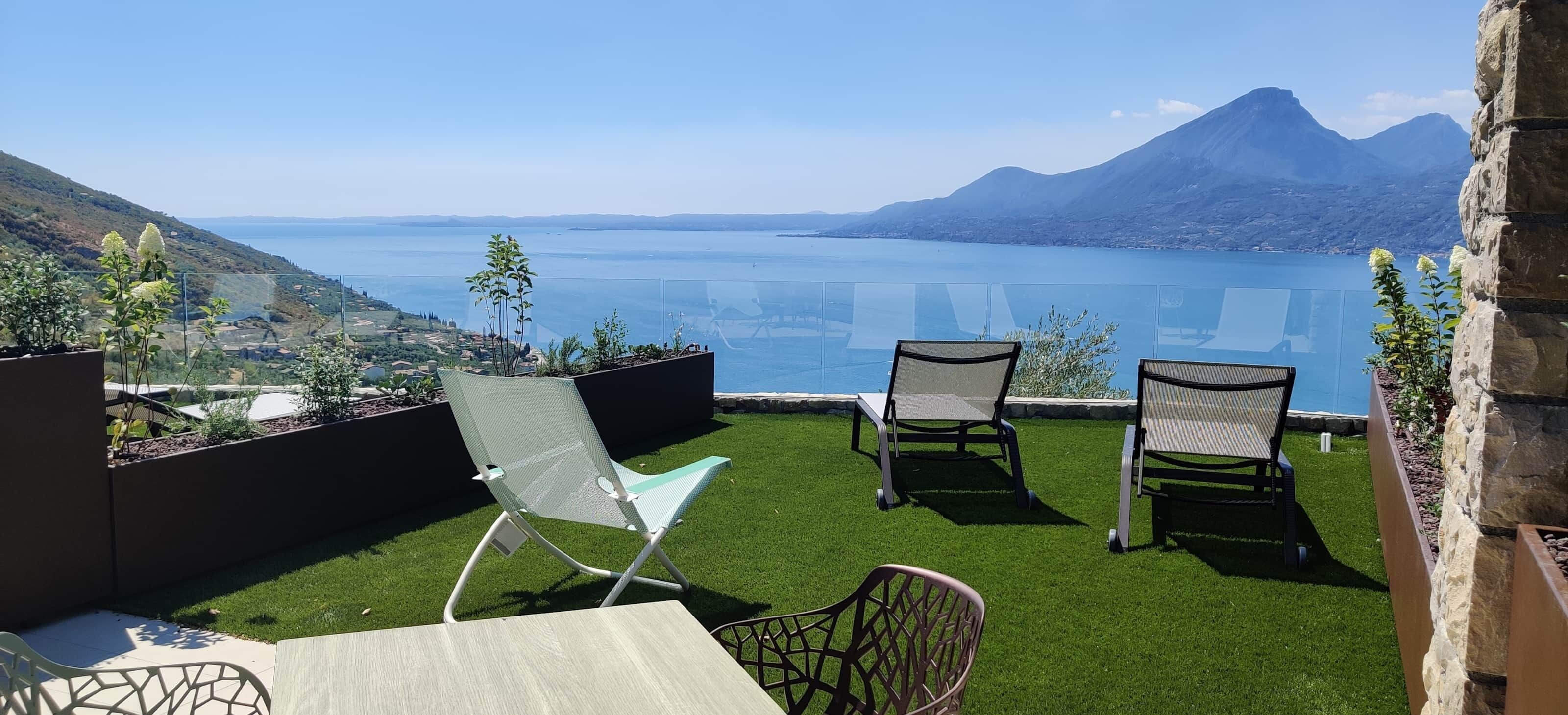Eine Terrasse mit zwei Stühlen und einem Tisch mit Blick auf einen See und Berge.