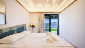 Una habitación de hotel moderna con una cama grande, vistas a montañas a través de un ventanal y una lámpara en el techo.