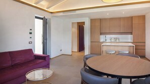 Una sala moderna con un sofá púrpura, una mesa redonda de madera y una mesa de centro de vidrio.
