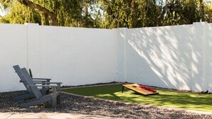Un jardin avec une piscine, une pelouse et un mur blanc.