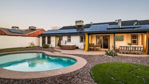 Une propriété résidentielle dotée d’une piscine, d’un patio avec mobilier d’extérieur et de panneaux solaires sur le toit.