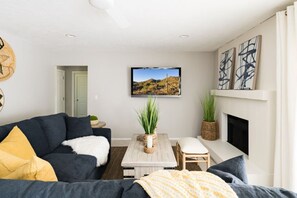 A modern living room with a sofa, a coffee table, and a fireplace. - Fun for the Whole Family w/Pool, Spa, Games + More (Scottsdale)