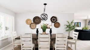 Un coin repas comprenant une table ronde, six chaises et des œuvres d’art décoratives accrochées au mur.
