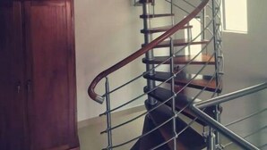 A spiral staircase with metal railings and wooden steps, leading to an upper floor.