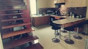 A modern kitchen with a central island, bar stools, and a staircase with wooden steps.