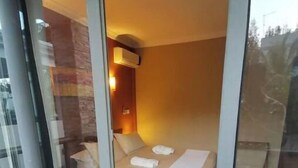 A modern bedroom with a bed, a bedside table, and a wall-mounted air conditioner.