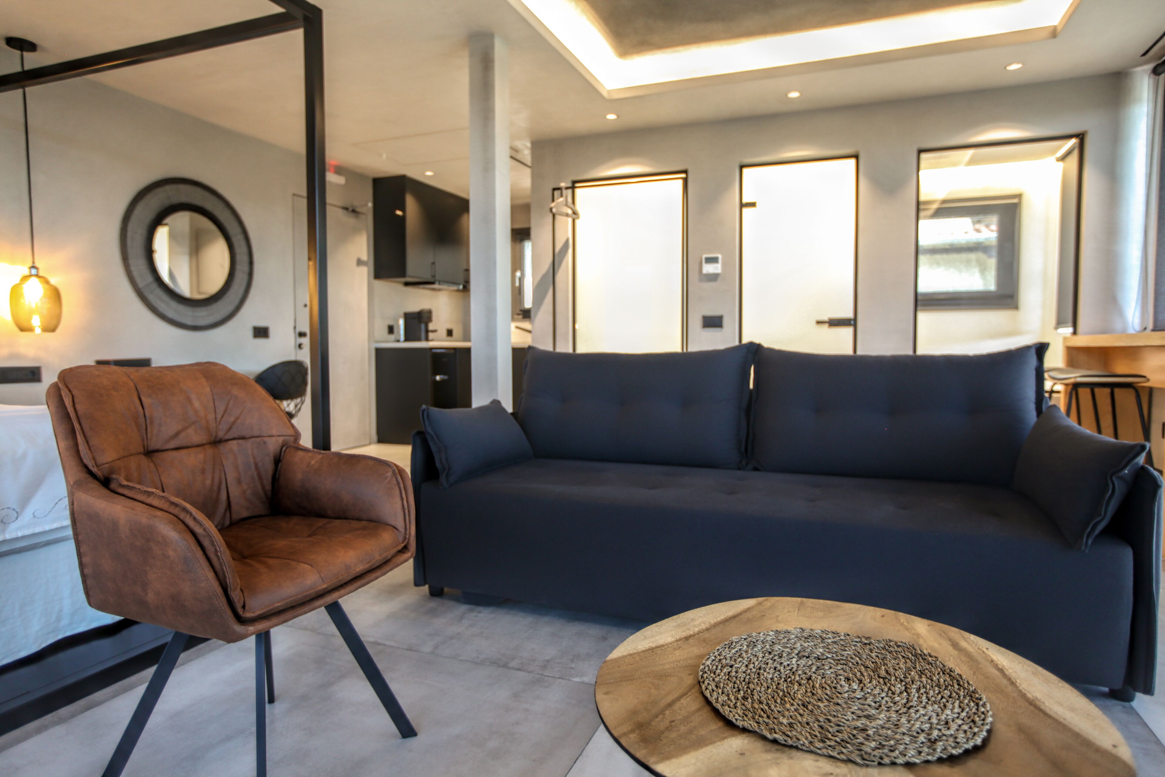 Una sala de estar moderna con un sillón de cuero, un sofá oscuro y una mesa de centro de madera.